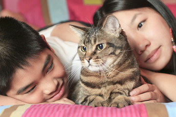 Asian kid lay on his bedroom with cat