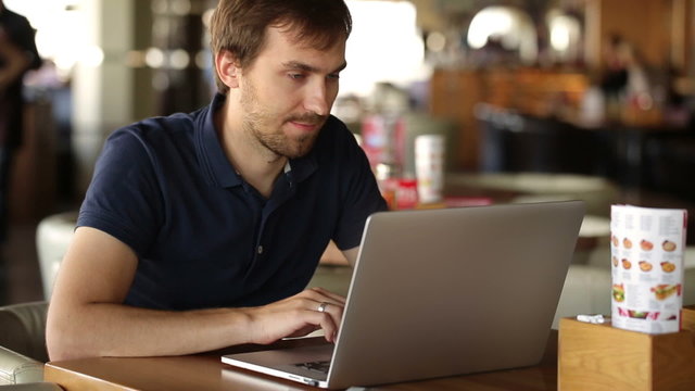 a man sitting in a cafe and working at a laptop