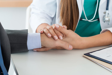 Close-up of friendly female medicine doctor's hand holding male