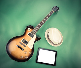 Electric guitar with notepad and old camera on green background