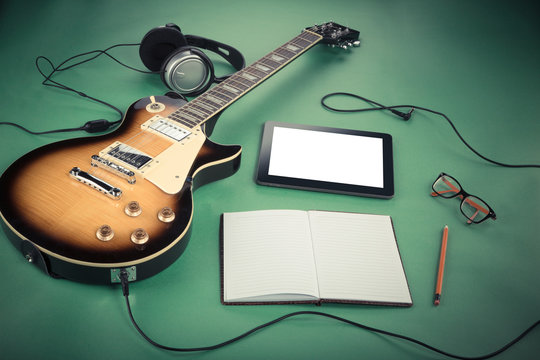 Electric guitar with notepad and old camera on green background - Powered by Adobe