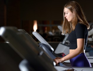 Fototapeta na wymiar Attractive young woman doing cardio exercise on treadmill at gym