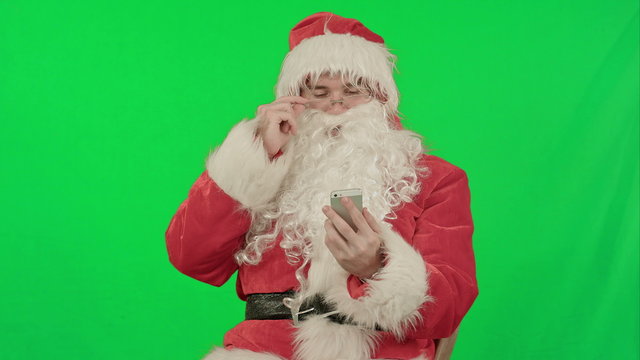 santa claus reads and sends text messages from his cell phone  on a Green Screen Chrome Key
