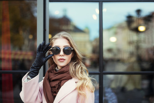 Fashion photo of beautiful young  woman with sunglasses. Model looking at camera. City lifestyle. Female fashion. Closeup portrait. Beautiful reflection background 