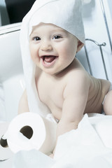 Toddler ripping up toilet paper in bathroom