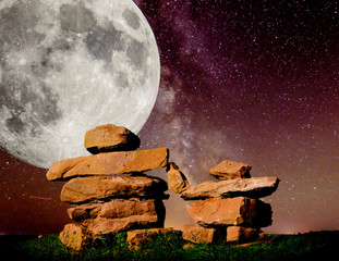 Pair of Inukshuks, parent and child against a large moon and milky-way