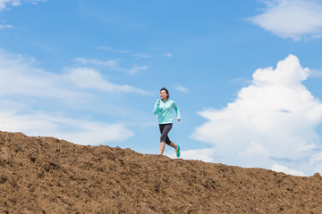 Fototapeta premium young woman running on trail with blue sky background