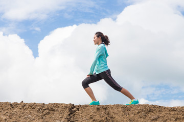 young woman stretching before Fitness and Exercise on mountain trail with blue sky background