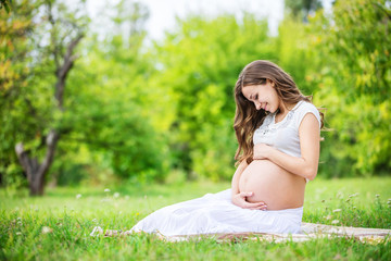 Beautiful pregnant woman relaxing outside in the park