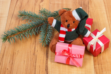 Teddy bear with colorful gifts for Christmas and spruce branches