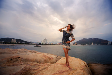 young long-legged girl barefoot stands tiptoe against sea