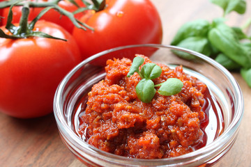 homemade red pesto with basil garnish on a wooden table
