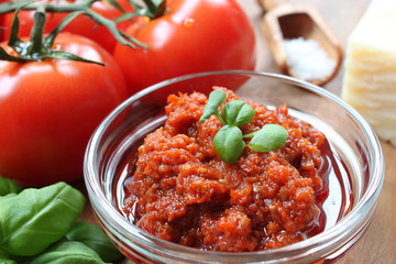 homemade red pesto with ingredients around and basil garnish