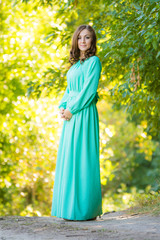 A girl in a long dress against a background of blurred forest