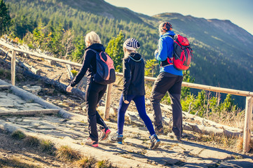 Parents with daughter hikers trekking in mountains.