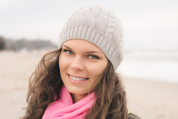Portrait of a smiling woman in a gray coat and a pink scarf in t
