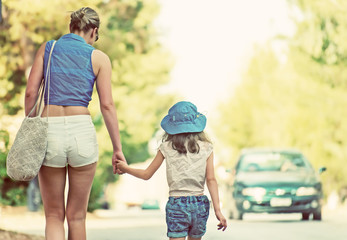 Woman with little girl walking on the roadside.
