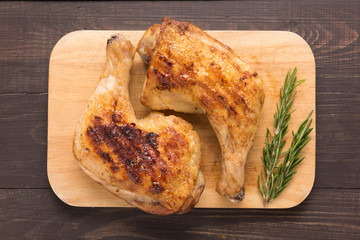 Grilled chicken lag and rosemary on wooden background