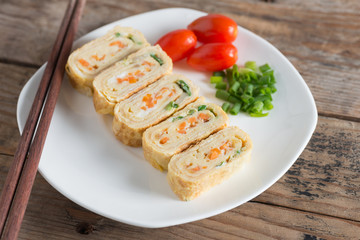 Eggs roll with carrot and onion on white plate.