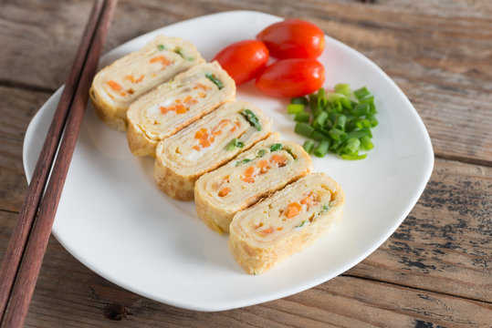 Eggs roll with carrot and onion on white plate.
