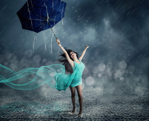 Junge Frau im Abendkleid tanzt im Regen 