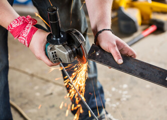 Worker with angle grinder for metal on workplace