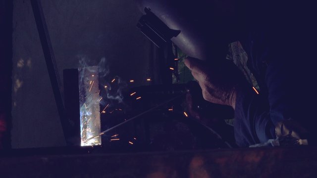 Shielded metal arc welding in workshop, male welder using electrode to melt the metal at the welding point.