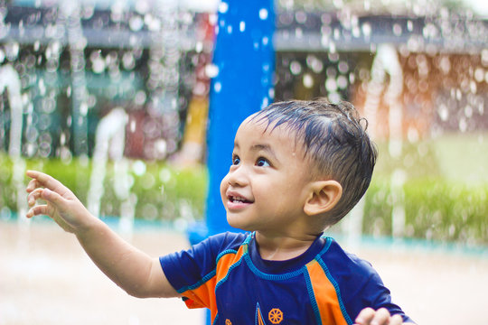 Boy standing in water fountain