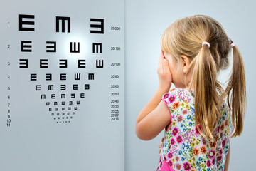 Little girl looking at vision test chart.