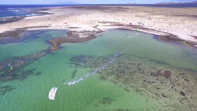 AERIAL: Flying above kiteboarders riding in big flat water lagoon