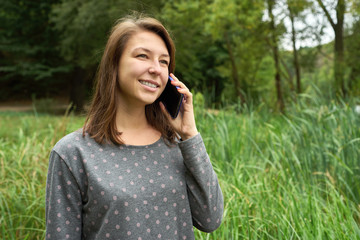 happy young woman talking on the phone in the forest