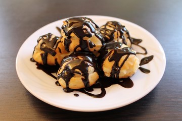 Profiteroles choux pastry, baked in the oven filling and custard poured chocolate and coffee