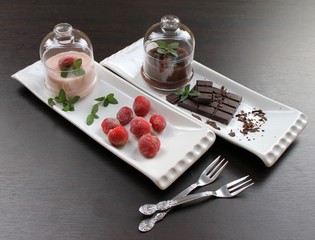 Fototapeta na wymiar Pudding with chocolate crumbs and strawberry pudding with frozen strawberries and mint in a glass cream bowls, on a white plate