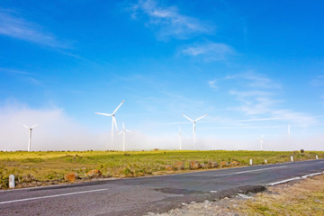 wind turbines along road - blue sky