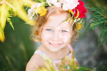 Little girl in flower wreath in the garden