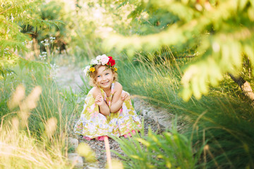 Little girl in flower wreath in the garden