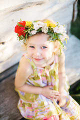 Obraz na płótnie Canvas Little girl in flower wreath in the garden