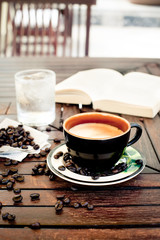 Cup of coffee, cappuccino with beans and a book.