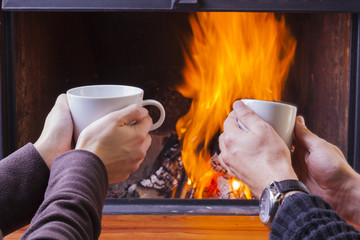 warming hands at fireplace with coffe and tea