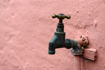 Wasserhahn an rosa Wand