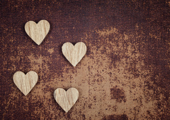 Four wooden hearts on  a grungy faux leather material background