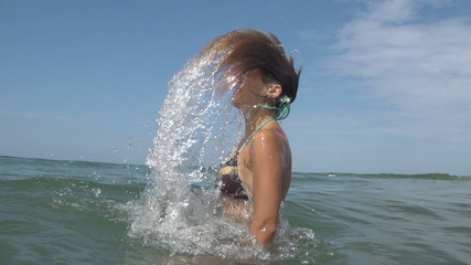 SLOW MOTION: Young woman splashing water with her hair