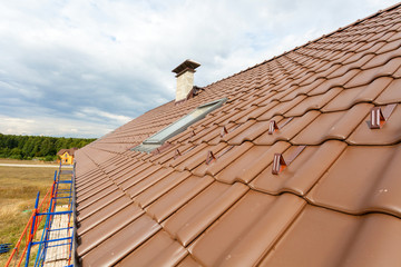 Naklejka premium New red tiled Roof with chimneys and skylight