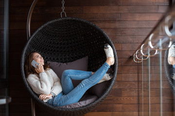 Woman lying in bubble chair and talking on the cellphone