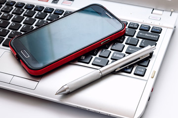 computer laptop with silver pen and mobile phone