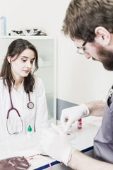 Fototapeta premium Doctor woman sitting at a table in a white coat male Doctor making blood