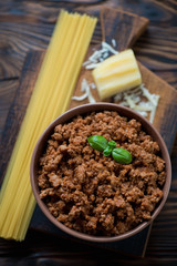 Bolognese sauce, raw spaghetti and parmesan. Above view, closeup