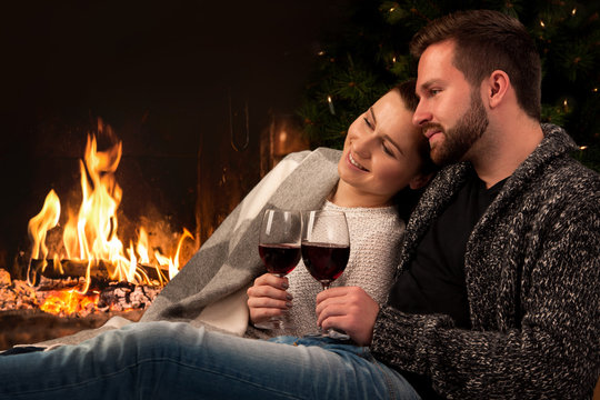 Couple With Glass Of Wine At Fireplace