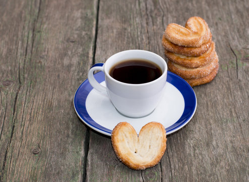 coffee on a saucer, and a column from cookies, on a wooden table