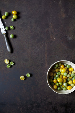 Overhead shot of yellow and green tomatoes on bowl on a rusty table